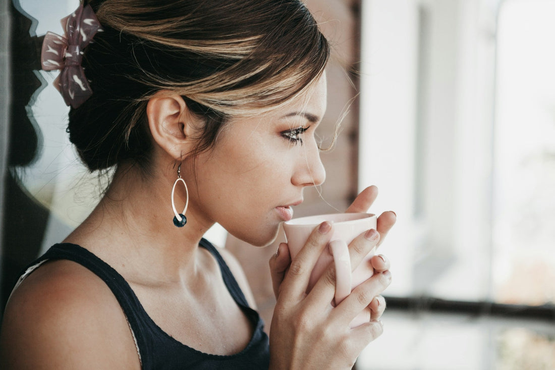 A woman stares into the distance while sipping a gentle cup of tea